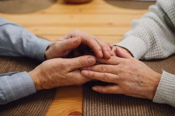Deux paires de mains posées l'une sur l'autre, en signe de soutien