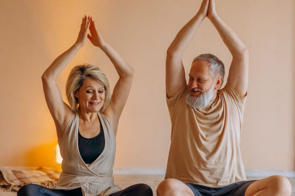 Deux participantes lors d'une séance de yoga adapté, bras levés
